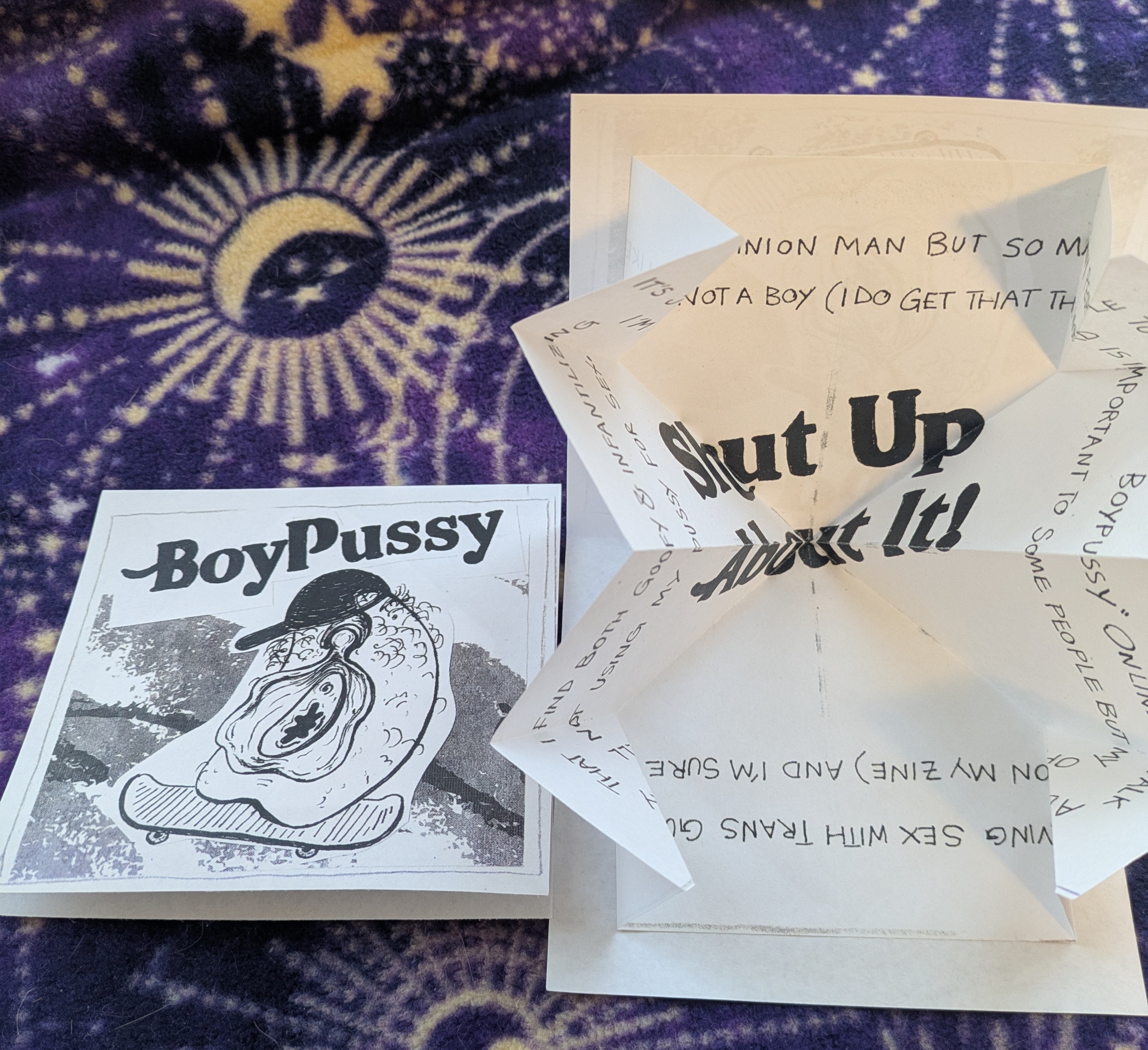 The cover of the zine “Boyp*ssy” and an unfolded copy of the zine next to it.